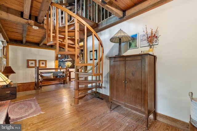 stairs featuring baseboards, beam ceiling, wooden ceiling, and hardwood / wood-style flooring