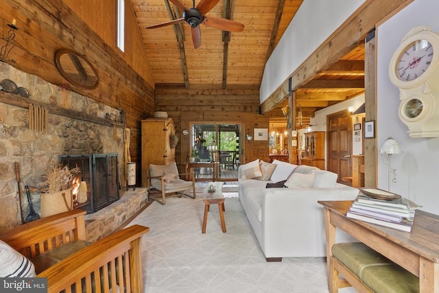 living room with high vaulted ceiling, wood walls, a stone fireplace, a ceiling fan, and wood ceiling