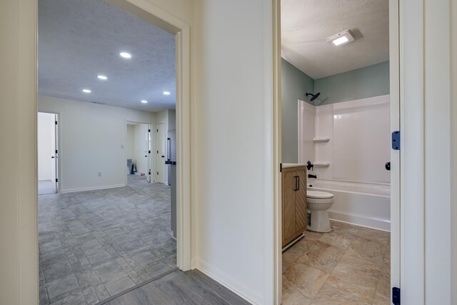 bathroom with shower / washtub combination, a textured ceiling, and toilet