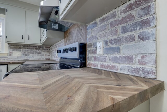 kitchen featuring stainless steel electric range oven, parquet floors, white cabinets, decorative backsplash, and exhaust hood