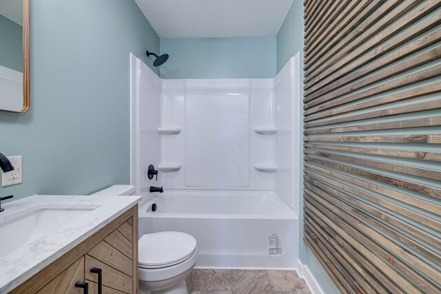 full bathroom featuring vanity, bathing tub / shower combination, toilet, and a textured ceiling