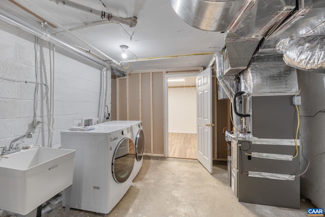 clothes washing area featuring heating unit, sink, and washer and dryer