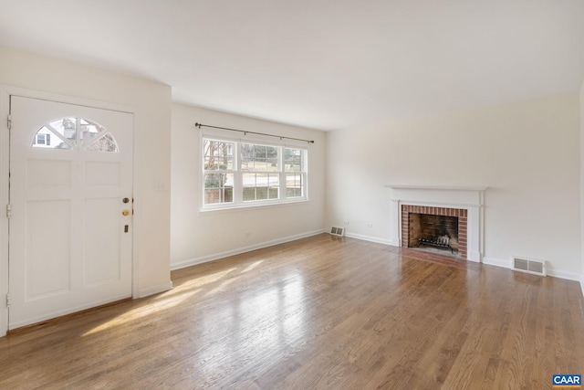 foyer entrance with wood-type flooring and a brick fireplace