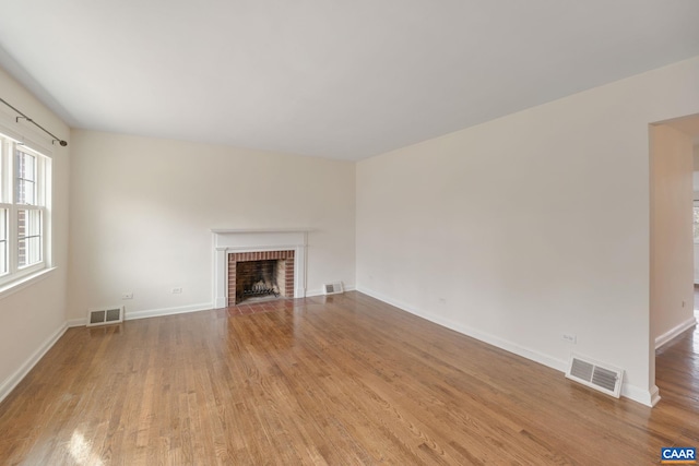 unfurnished living room with a brick fireplace and light wood-type flooring