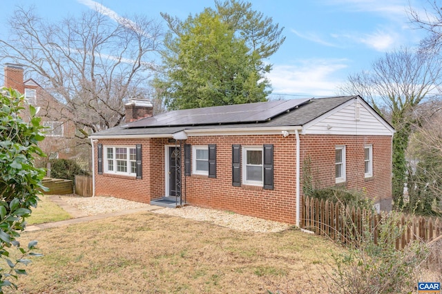 view of front of home featuring a front lawn and solar panels