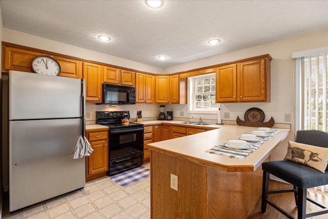 kitchen featuring a kitchen bar, sink, a textured ceiling, kitchen peninsula, and black appliances