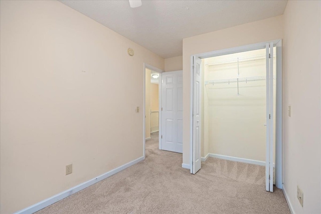 unfurnished bedroom featuring light carpet, a textured ceiling, and a closet