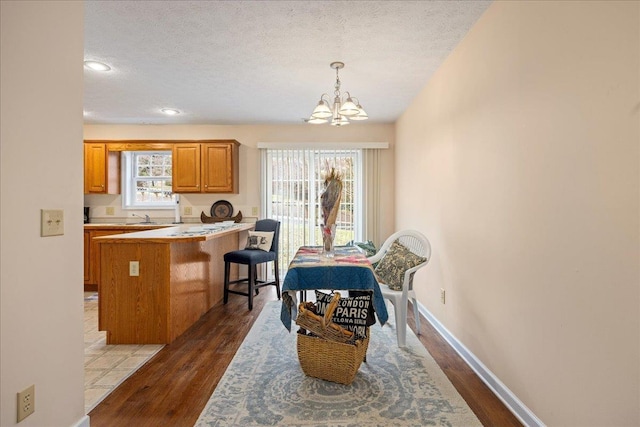 dining room with a notable chandelier, a wealth of natural light, a textured ceiling, and dark hardwood / wood-style flooring