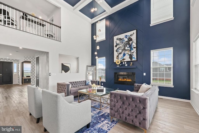 living area with a towering ceiling, a large fireplace, baseboards, and wood finished floors