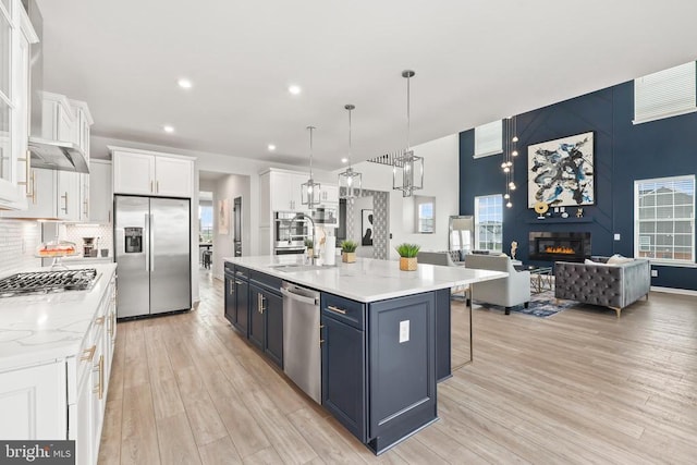 kitchen featuring a sink, light wood-type flooring, a fireplace, white cabinetry, and stainless steel appliances
