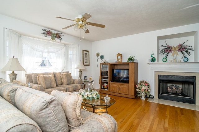 living area with a fireplace with flush hearth, light wood finished floors, and a ceiling fan