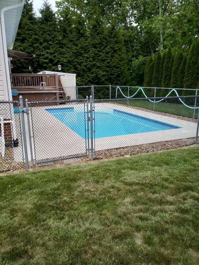 view of swimming pool with a lawn, fence, a fenced in pool, and a wooden deck