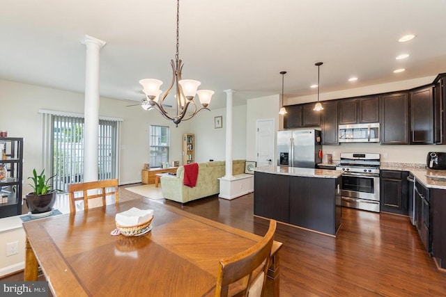 dining area with ceiling fan with notable chandelier, dark wood-type flooring, and decorative columns