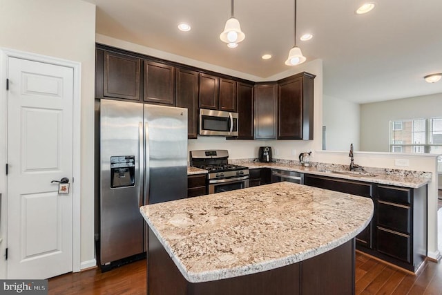 kitchen featuring hanging light fixtures, stainless steel appliances, sink, and a center island