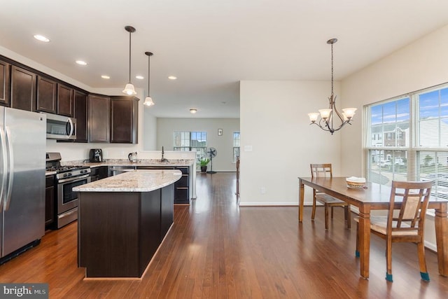 kitchen with appliances with stainless steel finishes, sink, pendant lighting, and dark brown cabinetry