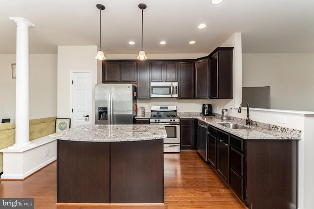 kitchen with dark brown cabinetry, appliances with stainless steel finishes, sink, and ornate columns