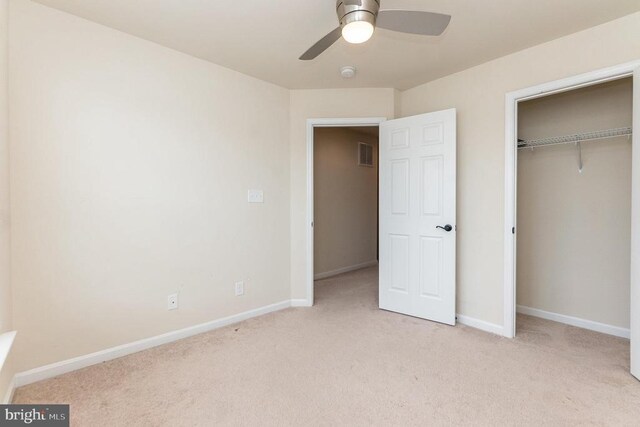 unfurnished bedroom with light colored carpet, a closet, and ceiling fan