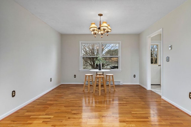 unfurnished dining area with a baseboard radiator, light hardwood / wood-style floors, and a chandelier