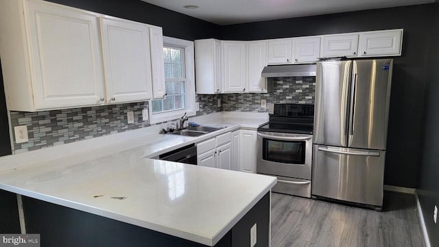 kitchen with sink, appliances with stainless steel finishes, kitchen peninsula, light hardwood / wood-style floors, and white cabinets