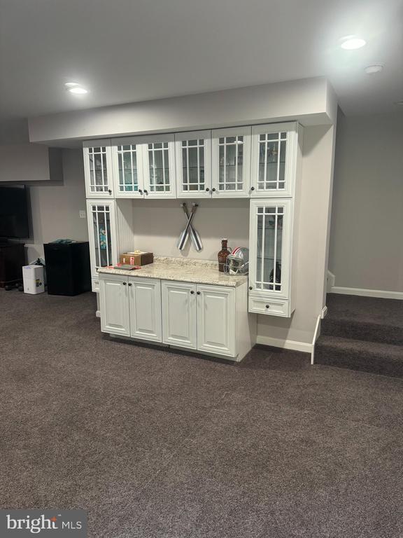 bar featuring white cabinetry, light stone countertops, and dark colored carpet