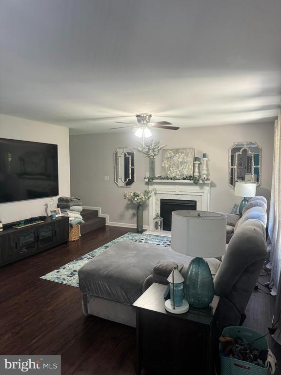 living room featuring dark wood-type flooring and ceiling fan