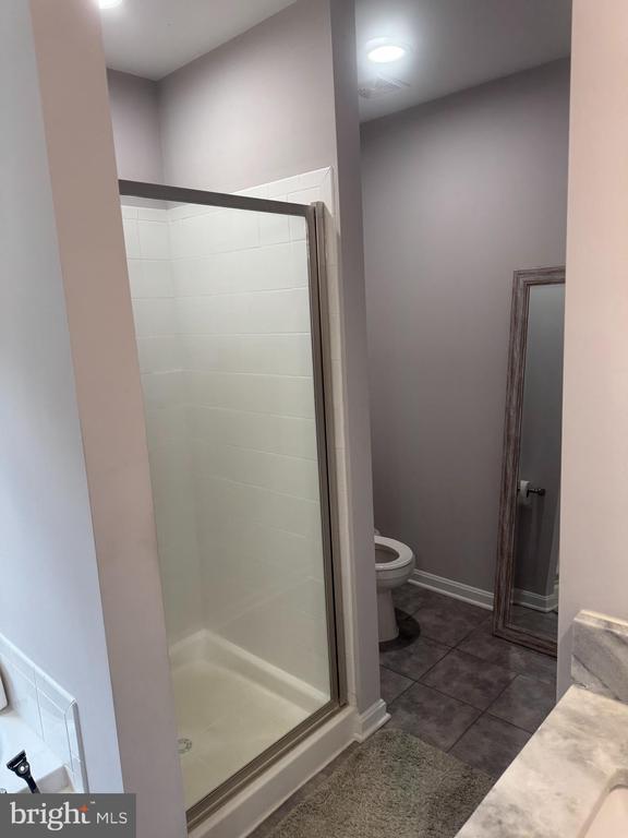 bathroom featuring tile patterned flooring, toilet, and walk in shower