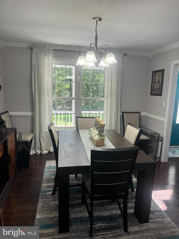 dining room with crown molding, dark hardwood / wood-style floors, and a notable chandelier