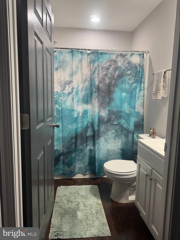 bathroom with vanity, hardwood / wood-style flooring, a shower with curtain, and toilet