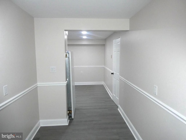 corridor with dark wood-type flooring and baseboards