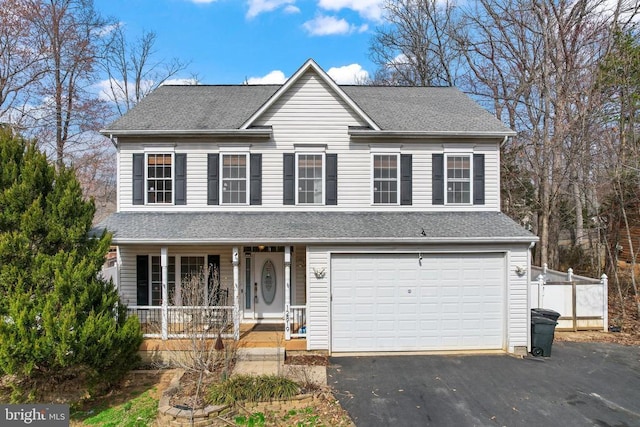 traditional-style house featuring covered porch, driveway, a garage, and roof with shingles