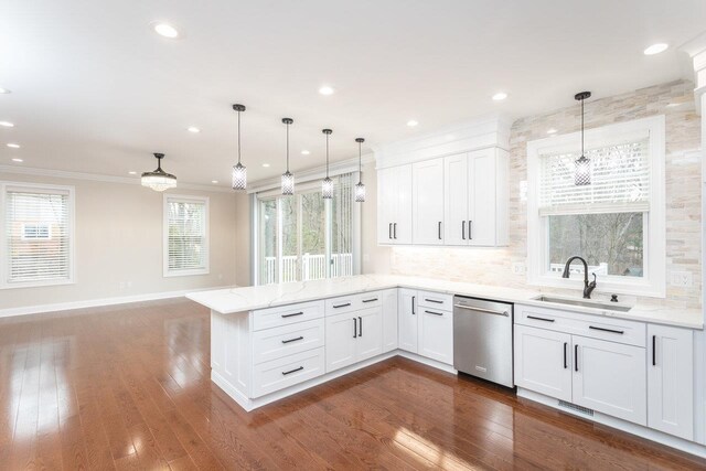 kitchen with sink, dishwasher, white cabinetry, light stone counters, and decorative light fixtures