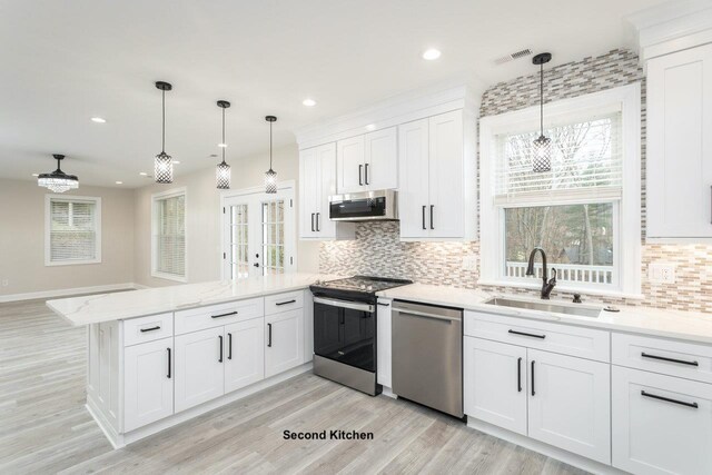 kitchen featuring sink, white cabinetry, decorative light fixtures, appliances with stainless steel finishes, and kitchen peninsula