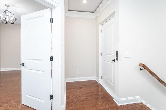 corridor with crown molding, dark hardwood / wood-style floors, and a chandelier