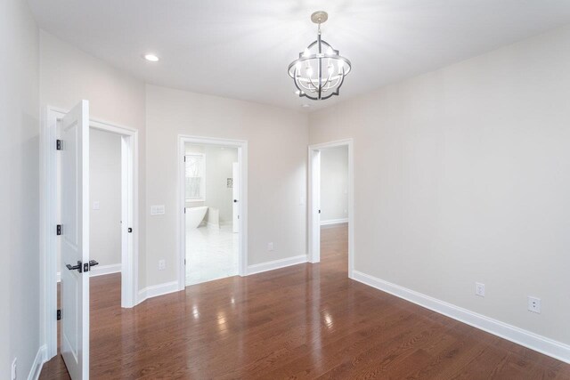 spare room with a notable chandelier and dark hardwood / wood-style floors