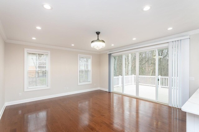 spare room with crown molding, a healthy amount of sunlight, and dark hardwood / wood-style floors