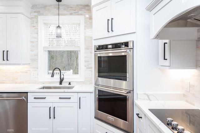 kitchen featuring light stone counters, appliances with stainless steel finishes, sink, and white cabinets