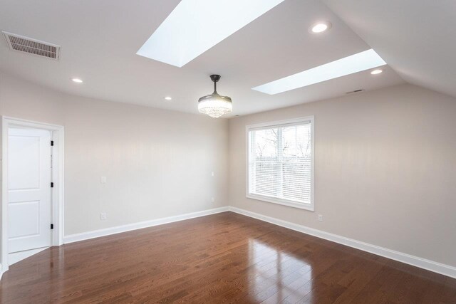 unfurnished room featuring lofted ceiling with skylight and dark hardwood / wood-style floors