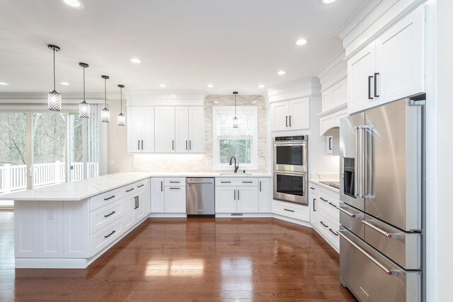 kitchen with stainless steel appliances, hanging light fixtures, white cabinets, and kitchen peninsula