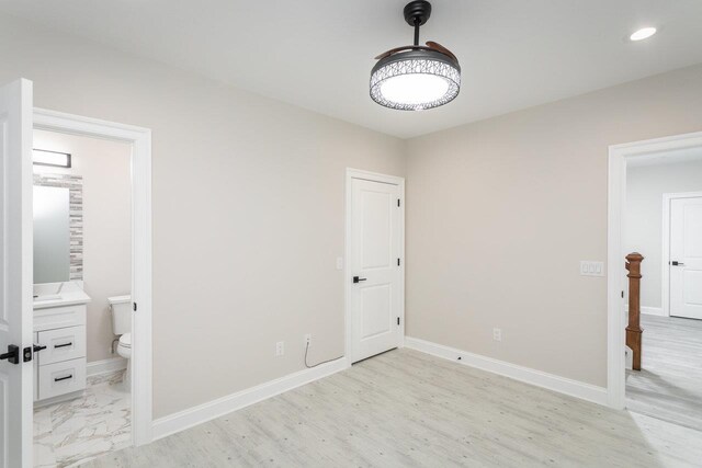 unfurnished bedroom featuring connected bathroom and light hardwood / wood-style floors