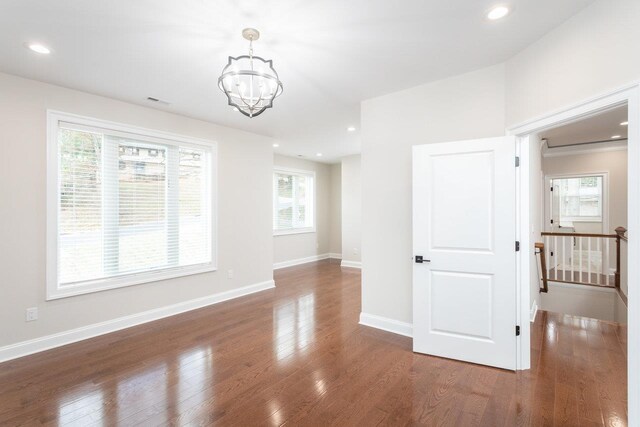 spare room featuring dark hardwood / wood-style flooring and a notable chandelier