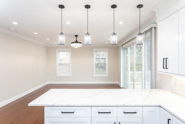 kitchen featuring hanging light fixtures, crown molding, light stone countertops, and white cabinets