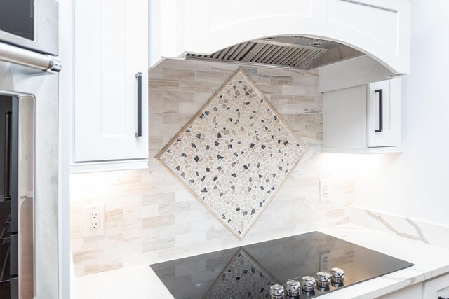 interior space featuring light stone counters, white cabinets, and premium range hood