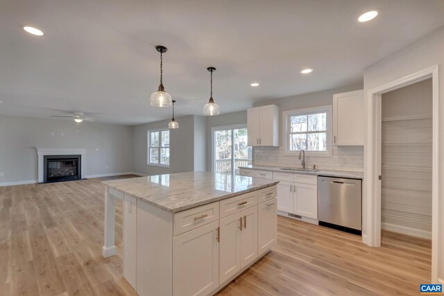 kitchen with sink, decorative light fixtures, dishwasher, a kitchen island, and white cabinets