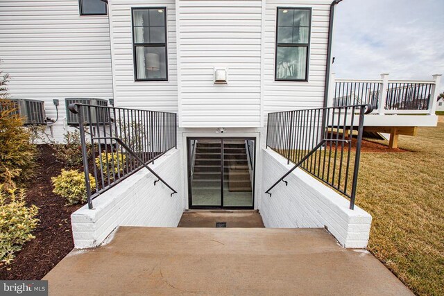 doorway to property with central AC and a lawn