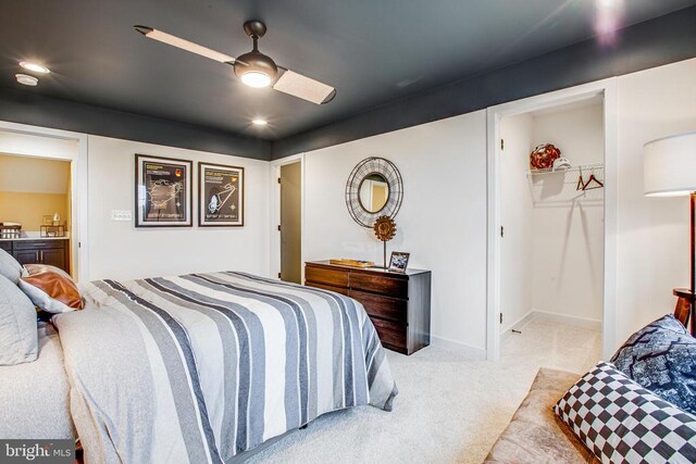 bedroom with ceiling fan, light colored carpet, a closet, and a walk in closet