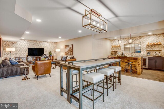 carpeted dining area with brick wall, bar area, and wine cooler