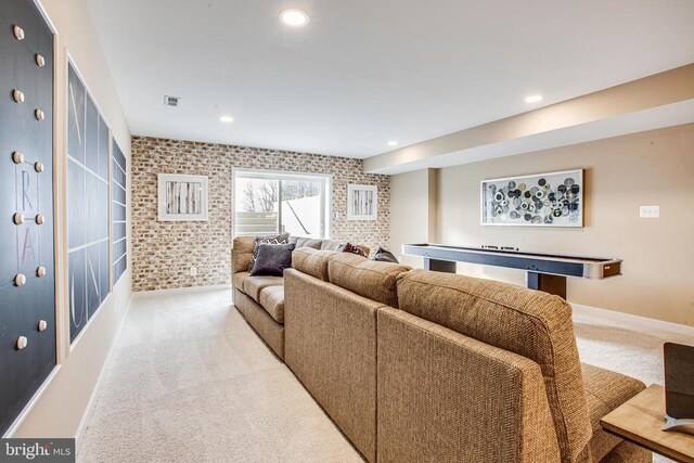 carpeted living room with brick wall