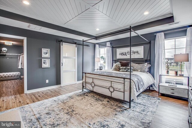 bedroom featuring a barn door, wooden ceiling, and light hardwood / wood-style floors