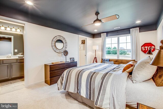 bedroom featuring ceiling fan, ensuite bath, sink, and light carpet