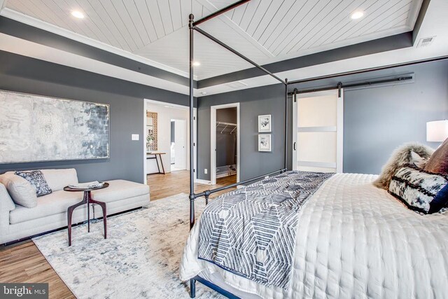 bedroom with a spacious closet, wooden ceiling, a closet, hardwood / wood-style flooring, and a barn door